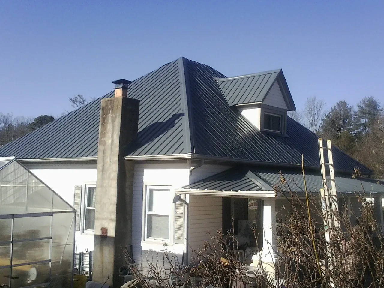 Dark blue standing seam metal roof on a white farmhouse with dormer — Slate & Tile Roof Repair by Roofing Brothers in Capon Bridge