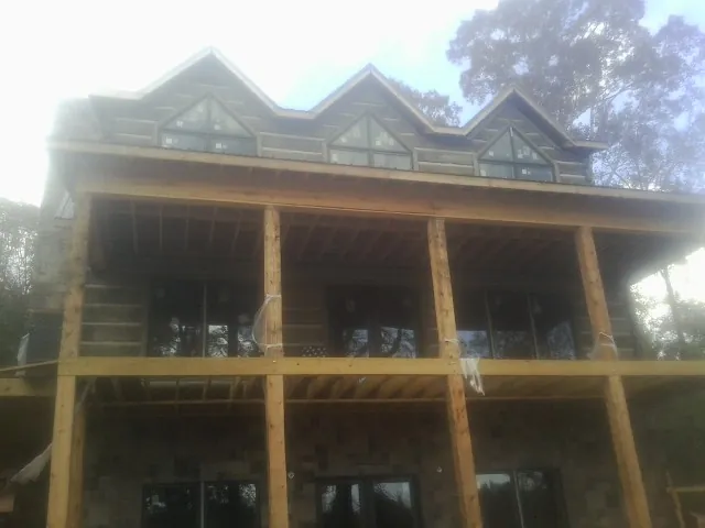 Dormers and porch framing on a large log home under construction — Roof Coating work by our crew in Capon Bridge