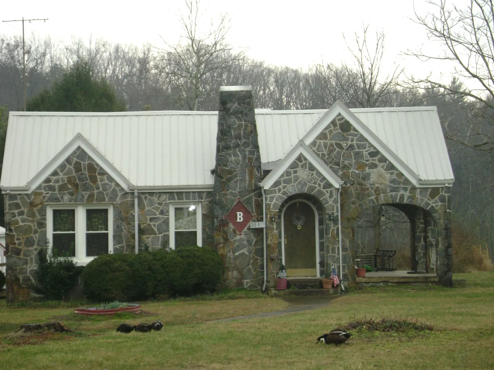 White metal roof on a stone cottage with steep gables in Capon Bridge