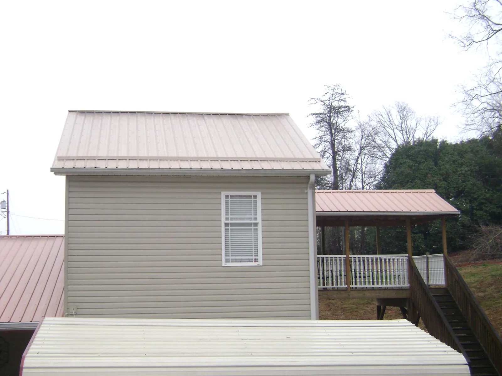 Tan metal roofs on a two story addition and attached porch, from a Roof Replacement job in Capon Bridge