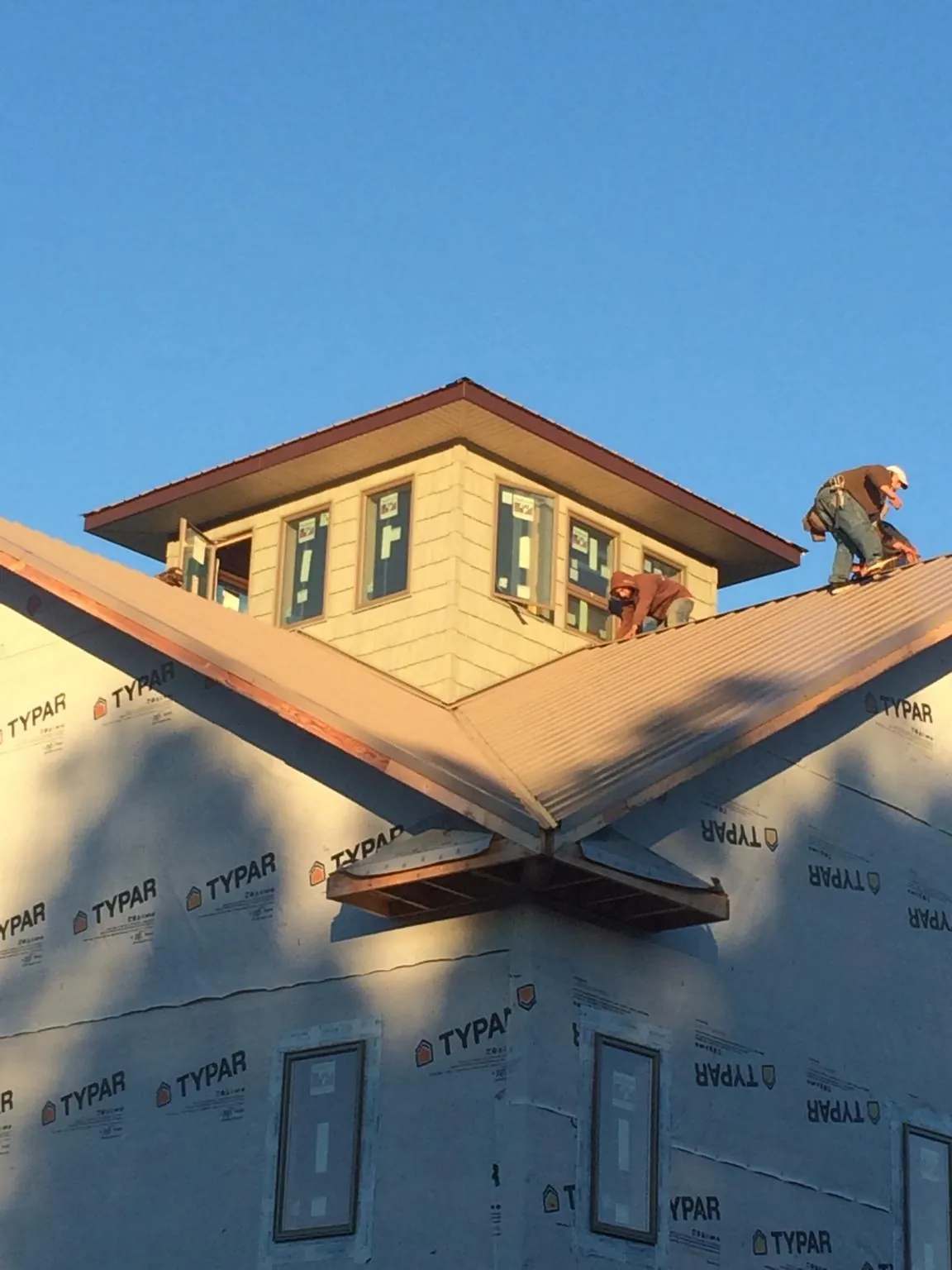 Roofers working around a rooftop cupola on a new metal roof at sunset — Roof Waterproofing in Capon Bridge by Roofing Brothers